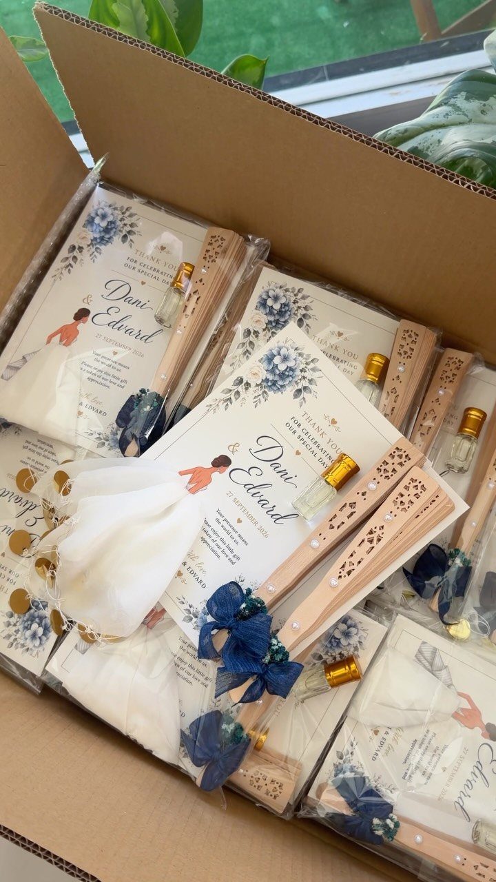 Wedding invitation sets with floral cards, wooden fans, and perfume bottles in a box