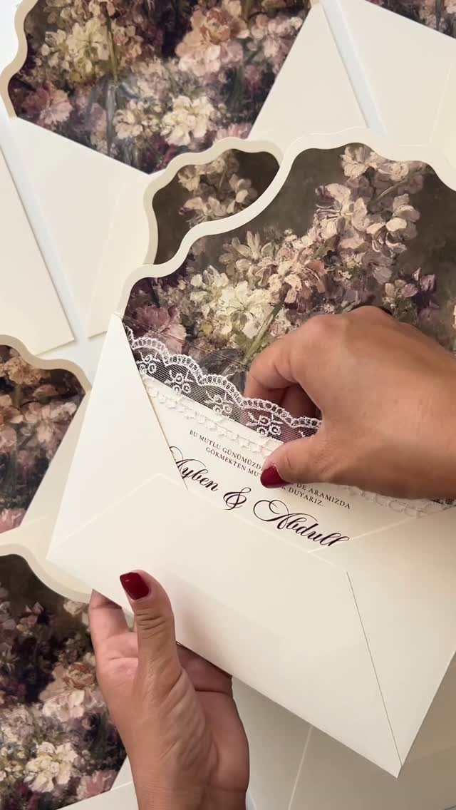 Wedding invitation with floral patterns and lace detail being pulled from white envelope