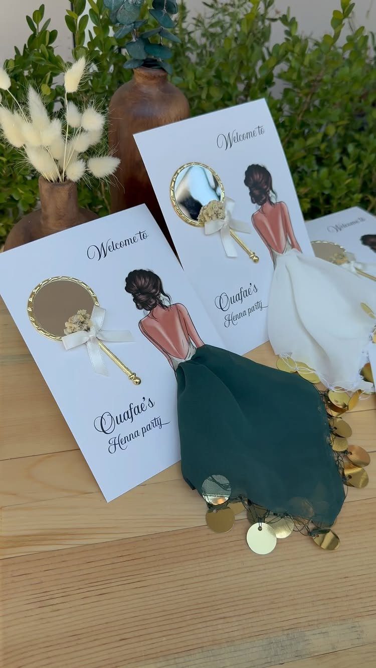 Invitation cards with illustrated women wearing real fabric dresses and gold sequins.