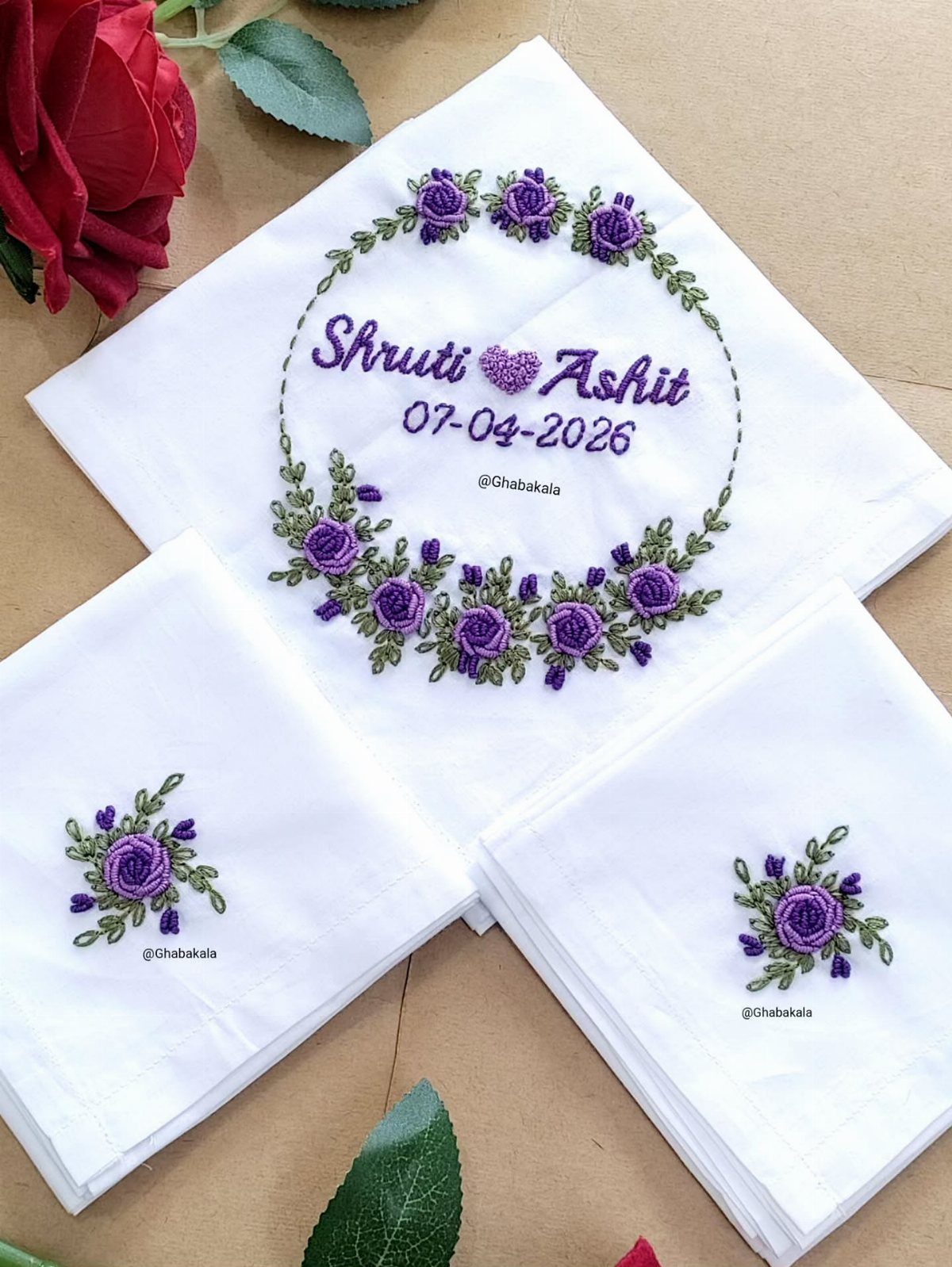 White handkerchiefs with purple floral embroidery and wedding names and date printed on them.