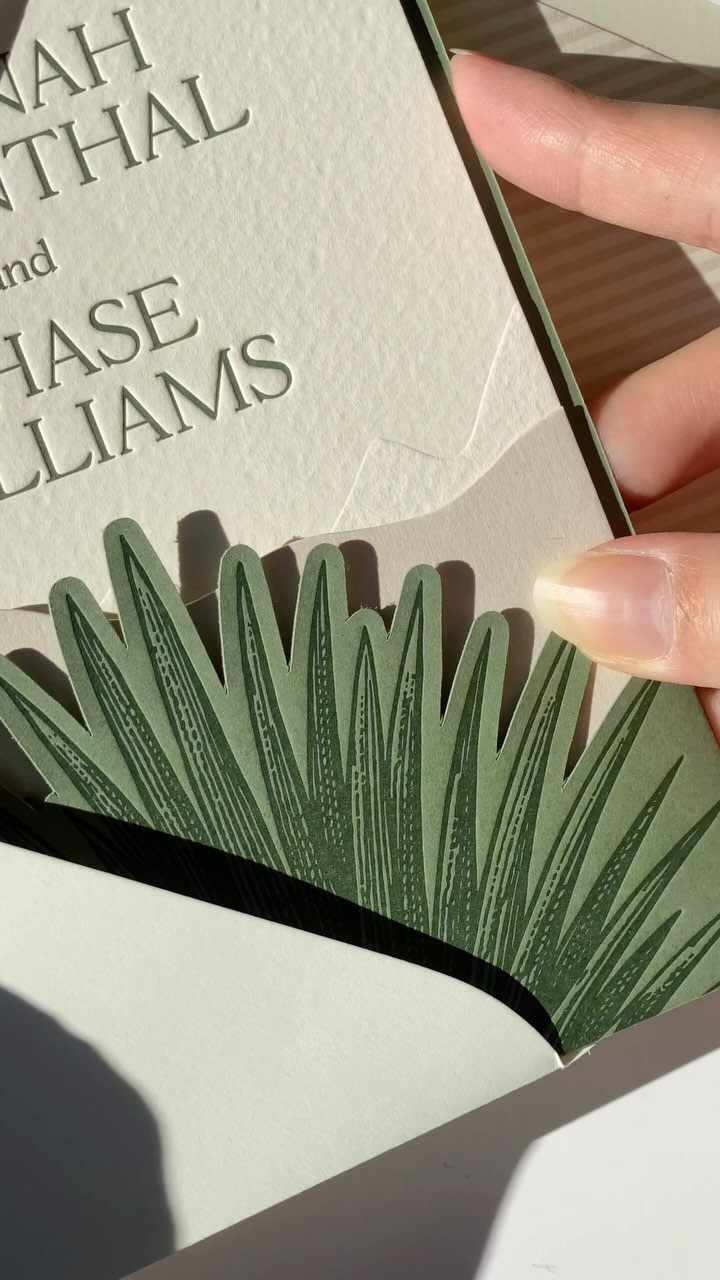 Wedding invitation with black text and a green botanical leaf envelope liner.