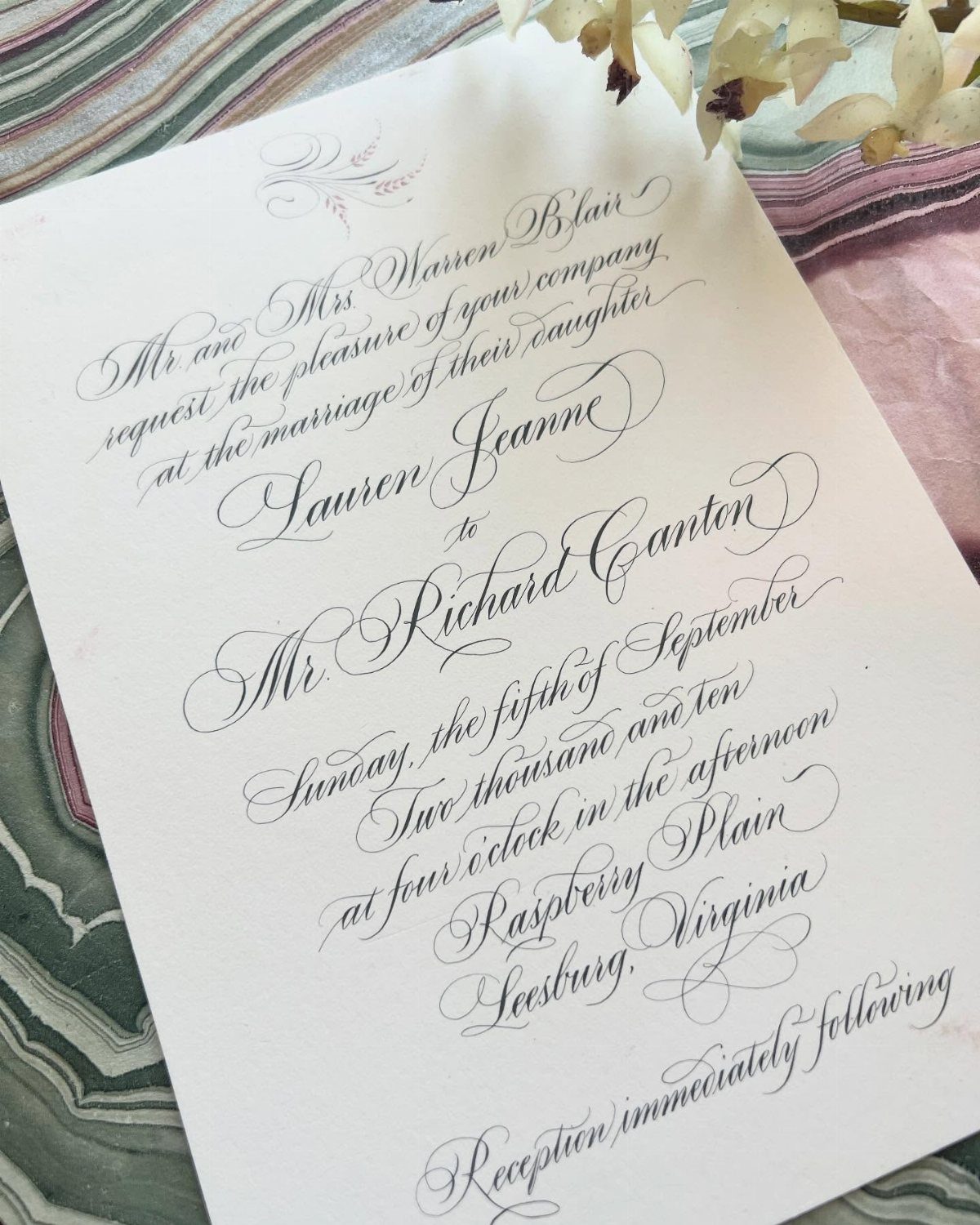 Wedding invitation with elegant black hand-lettered calligraphy on a white card.
