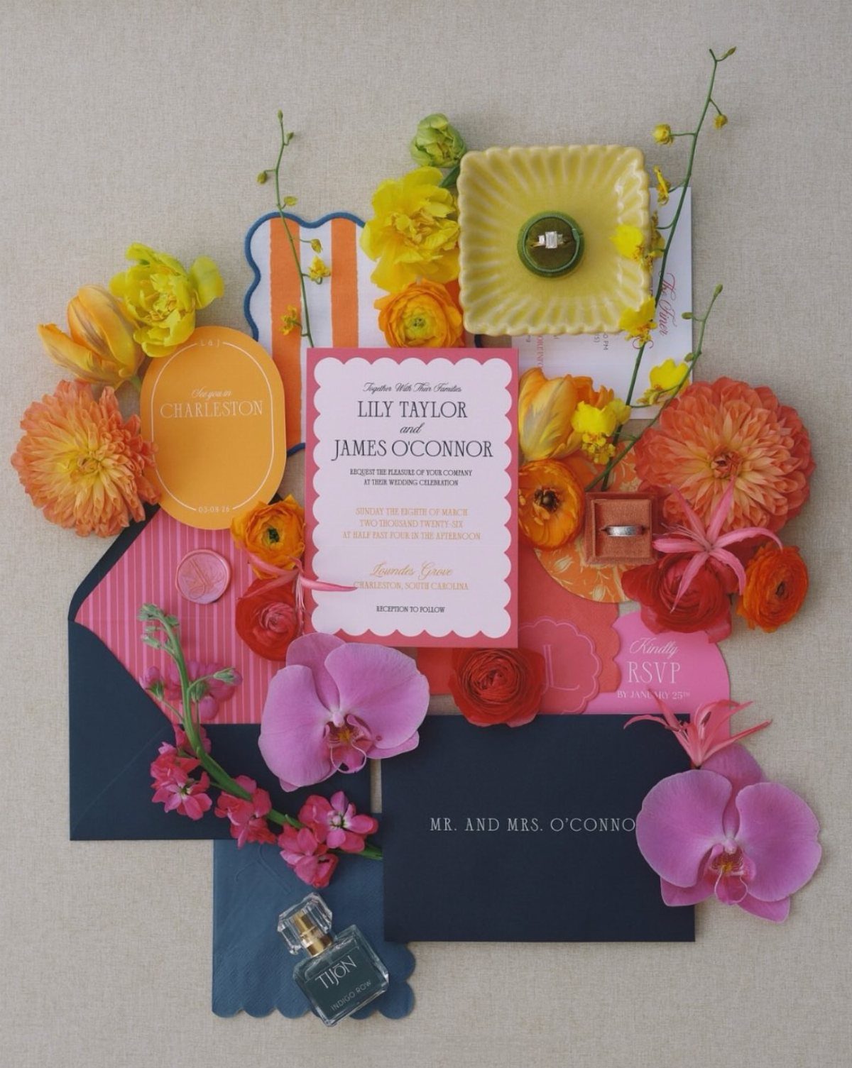 Colorful wedding invitations in pink and navy surrounded by vibrant spring flowers.