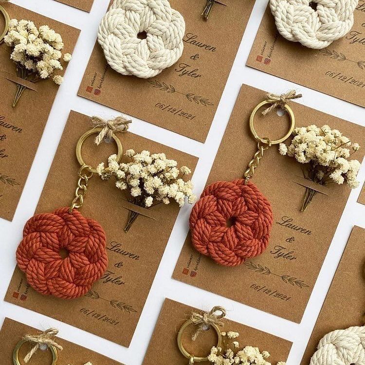 Crocheted circular keychains on brown wedding favor tags with dried white flowers.