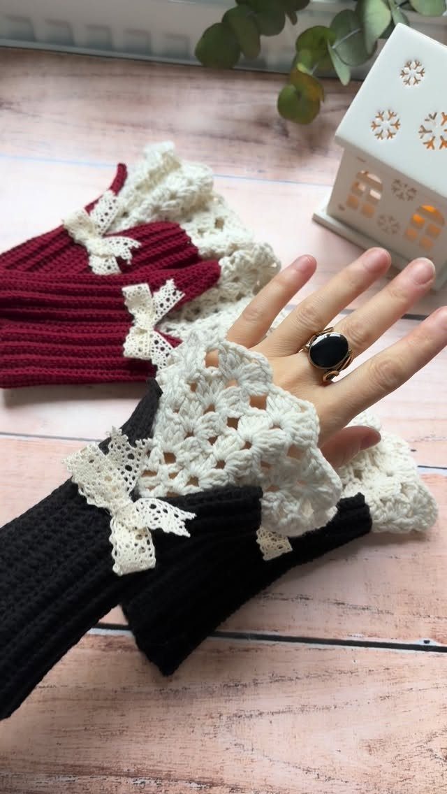 Black and burgundy crochet fingerless gloves with white lace trim on wooden surface