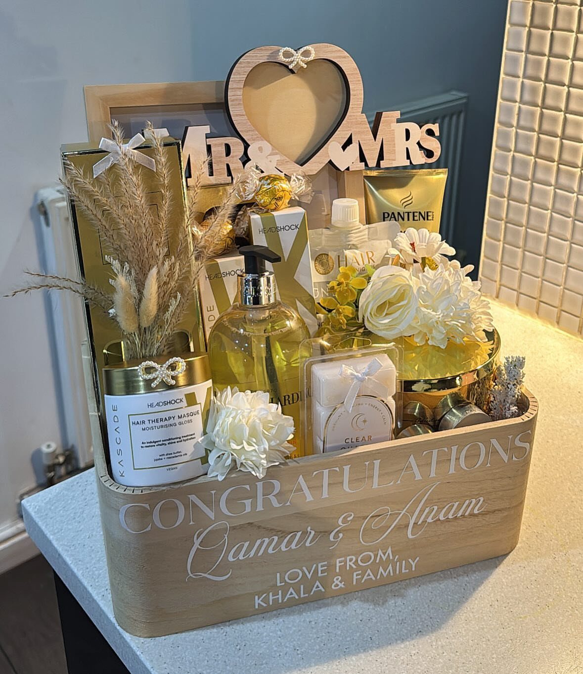 Wooden wedding gift box containing toiletries, white flowers, and a Mr and Mrs sign.