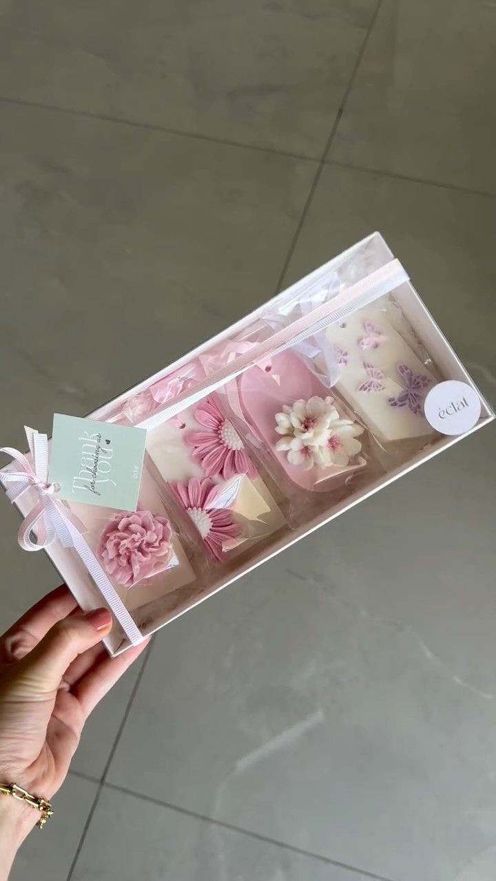 Decorative pink and white flower soaps in a clear gift box with ribbon.