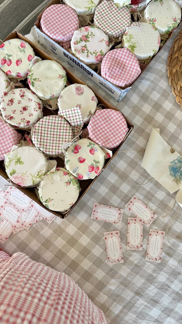 Fabric-covered jam jars in trays on a checkered tablecloth with small gift tags.