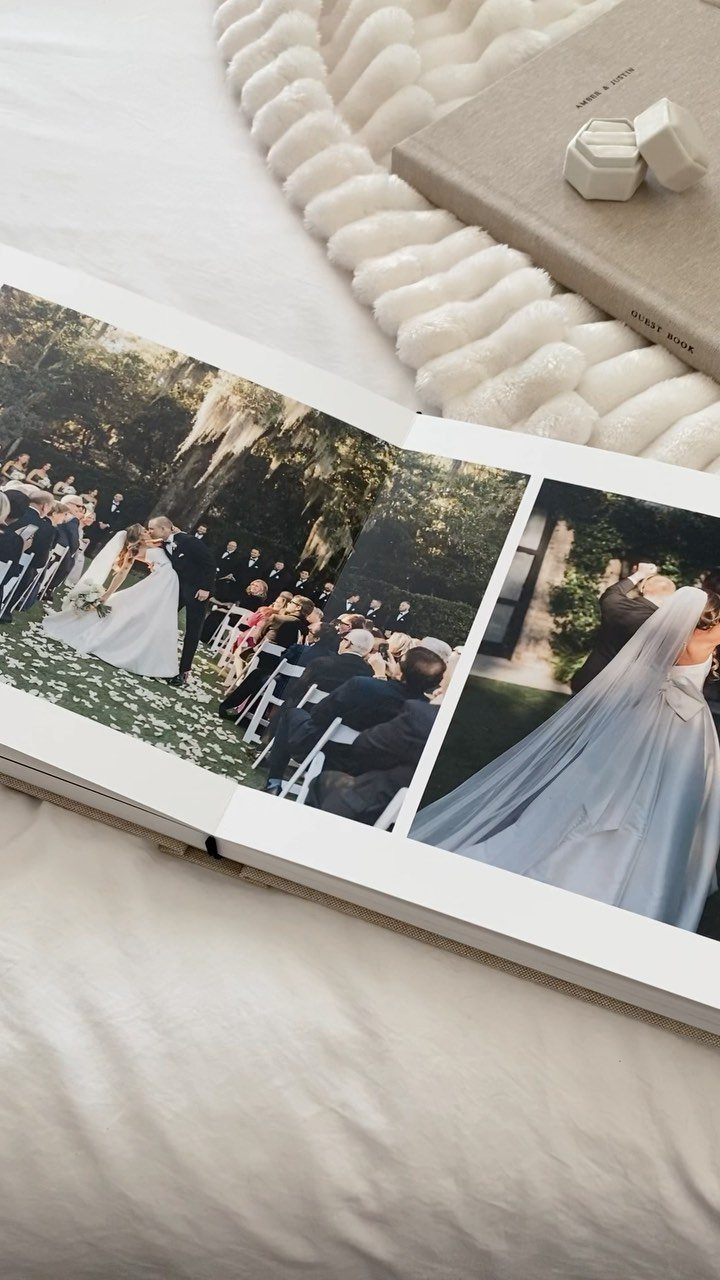 Open white photo album showing wedding ceremony pictures on a white fabric background