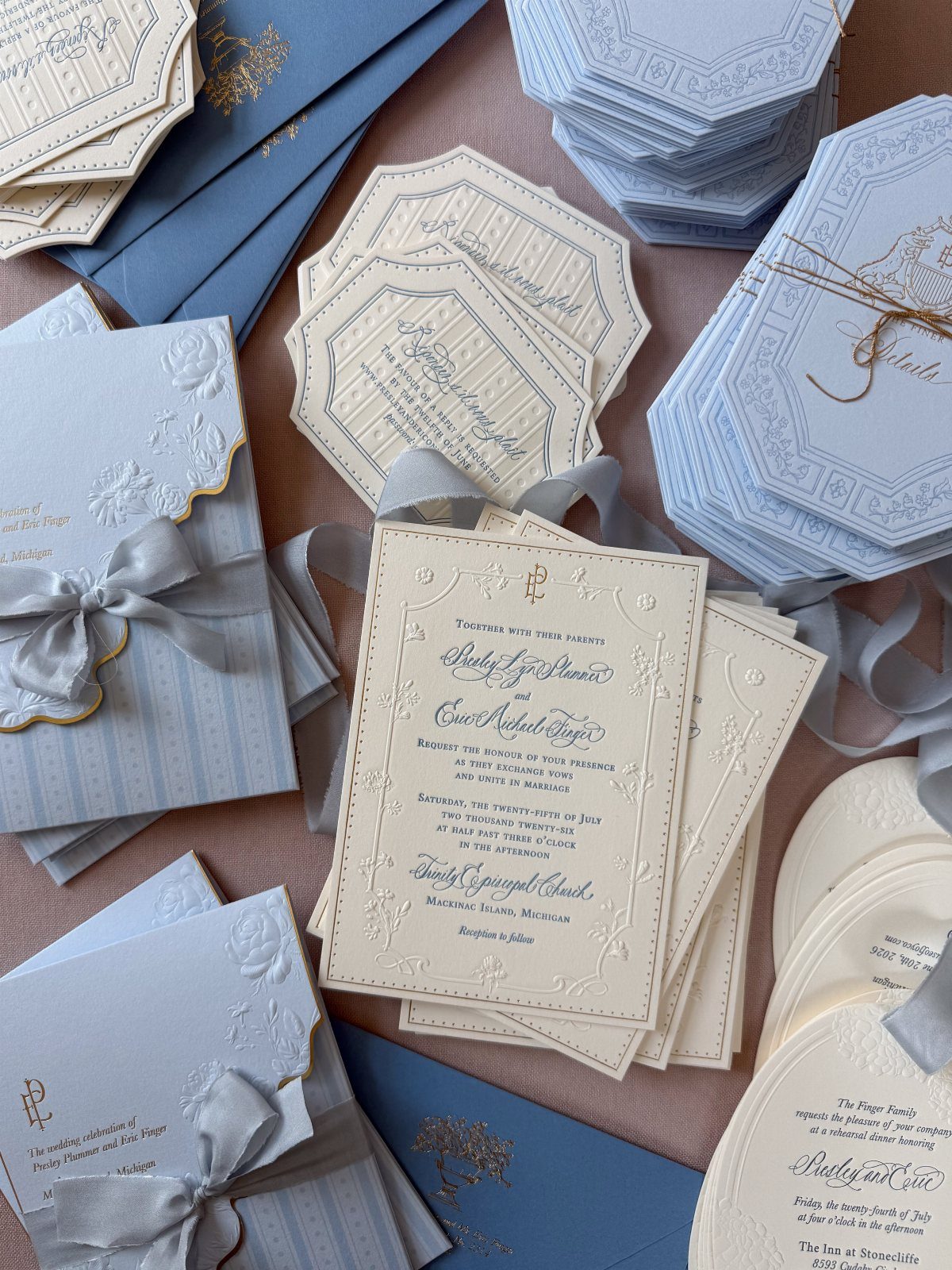 Wedding stationery with embossed floral designs and calligraphy in white and blue tones.