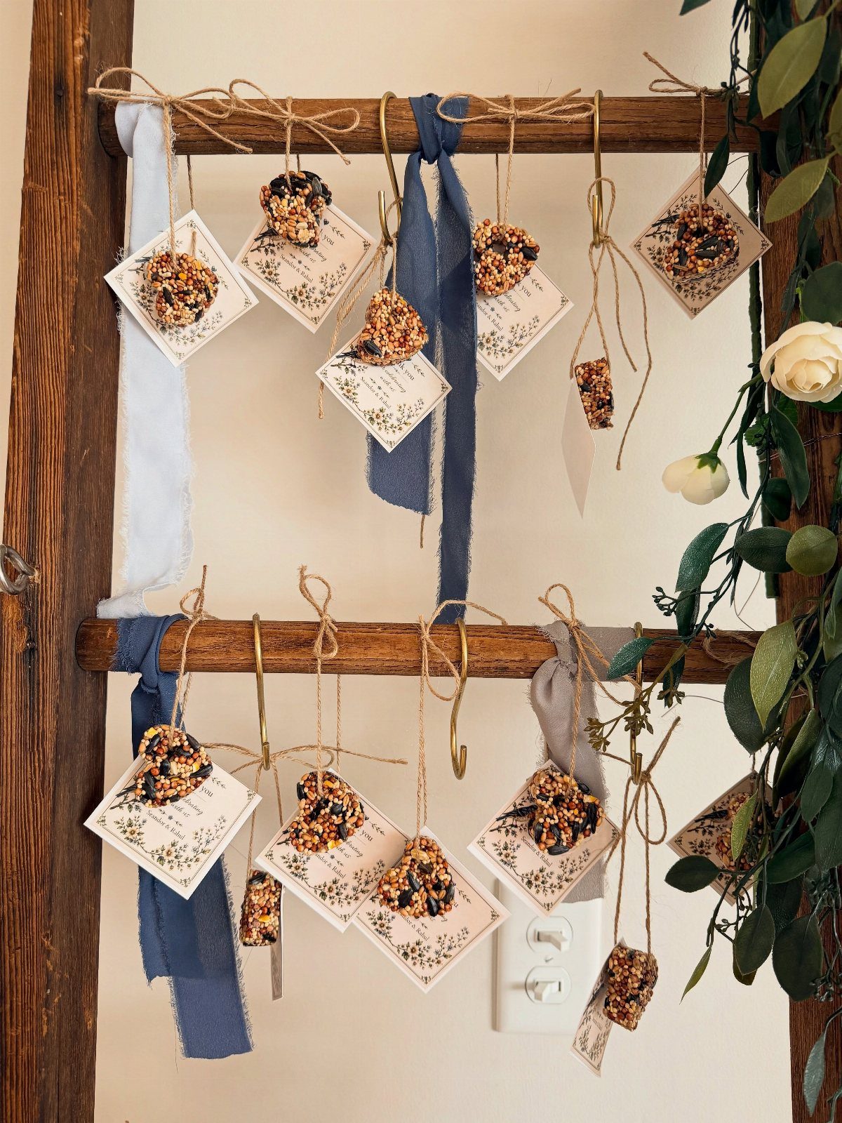 Heart-shaped birdseed ornaments with tags hanging from a rustic wooden ladder.