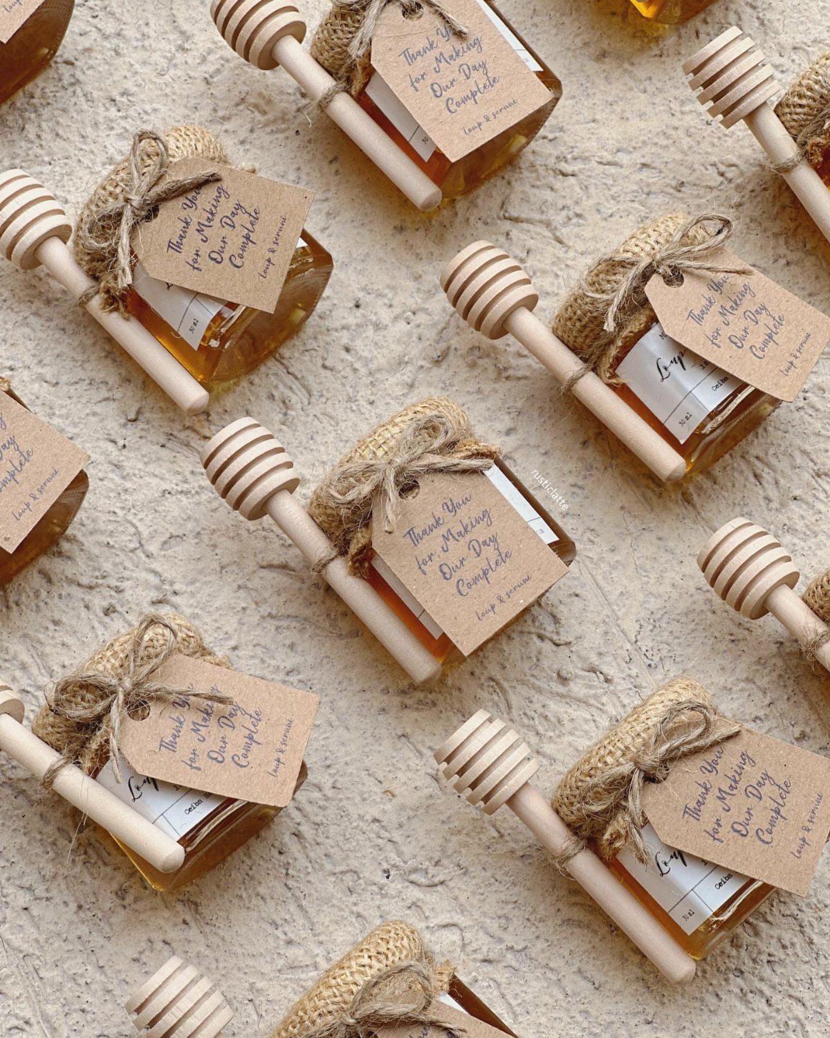 Small honey jars with burlap covers, wooden dippers, and personalized gift tags.