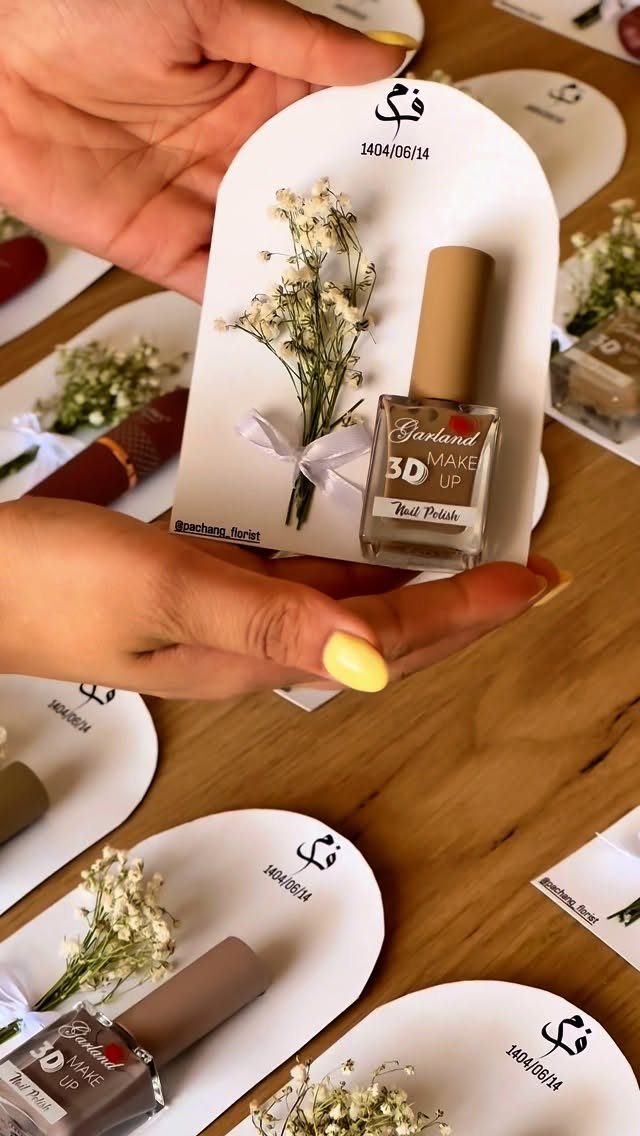 Nail polish and baby's breath flowers attached to a white arched gift card.