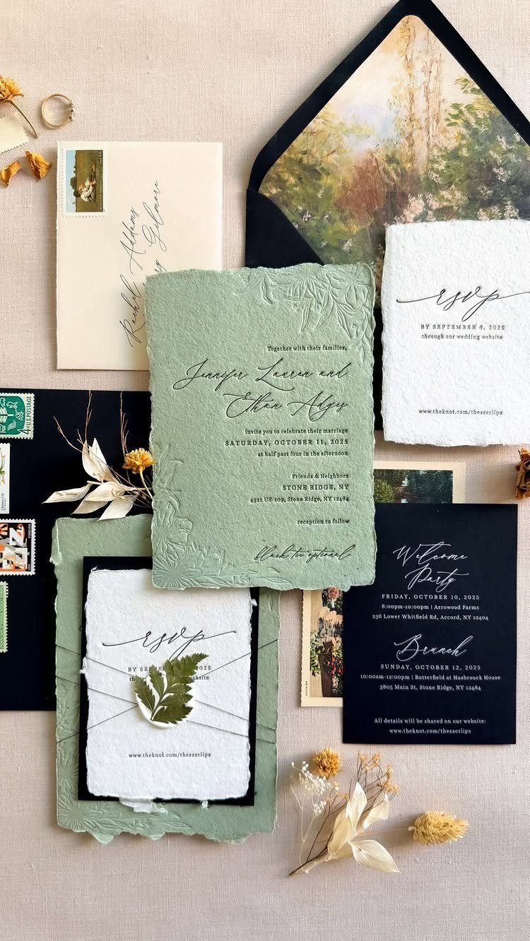 Wedding invitation suite with sage green and black cards on neutral fabric.