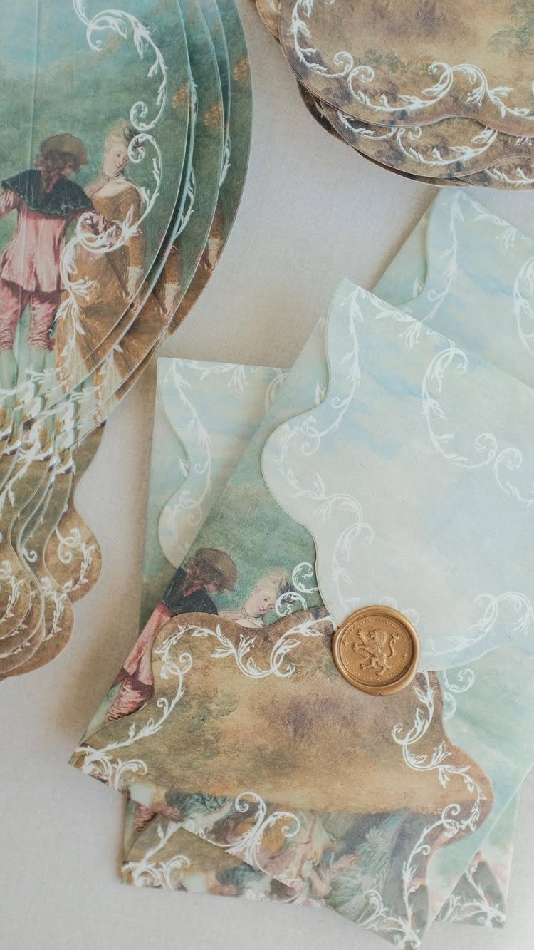 Scalloped light blue wedding stationery with classical paintings and a gold wax seal.