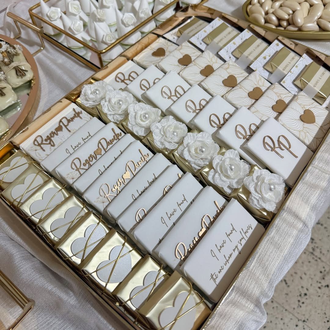 Customized white and gold chocolate bars arranged on a gold tray with flowers.