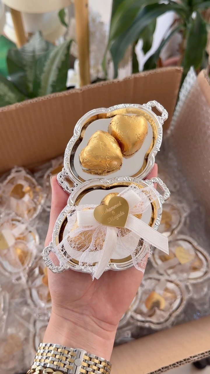 Gold heart-shaped chocolates in ornate silver trays with white tulle and ribbons.