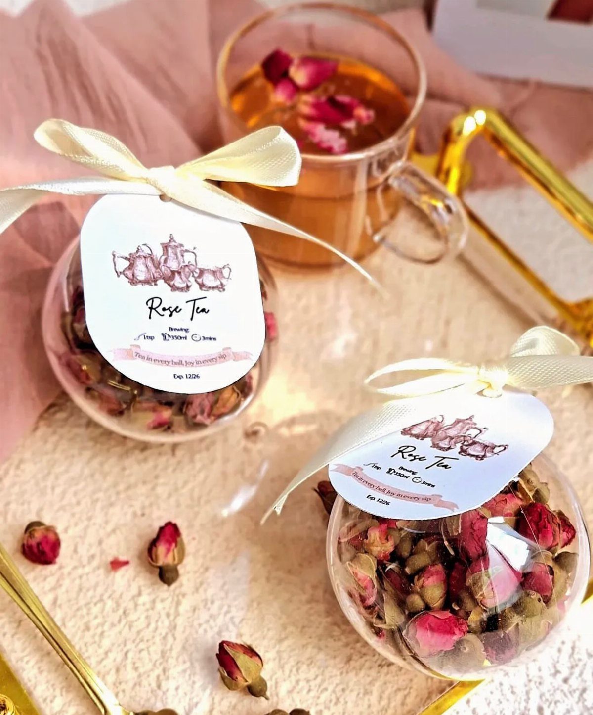 Dried rose tea in round clear containers with white ribbons and custom labels.