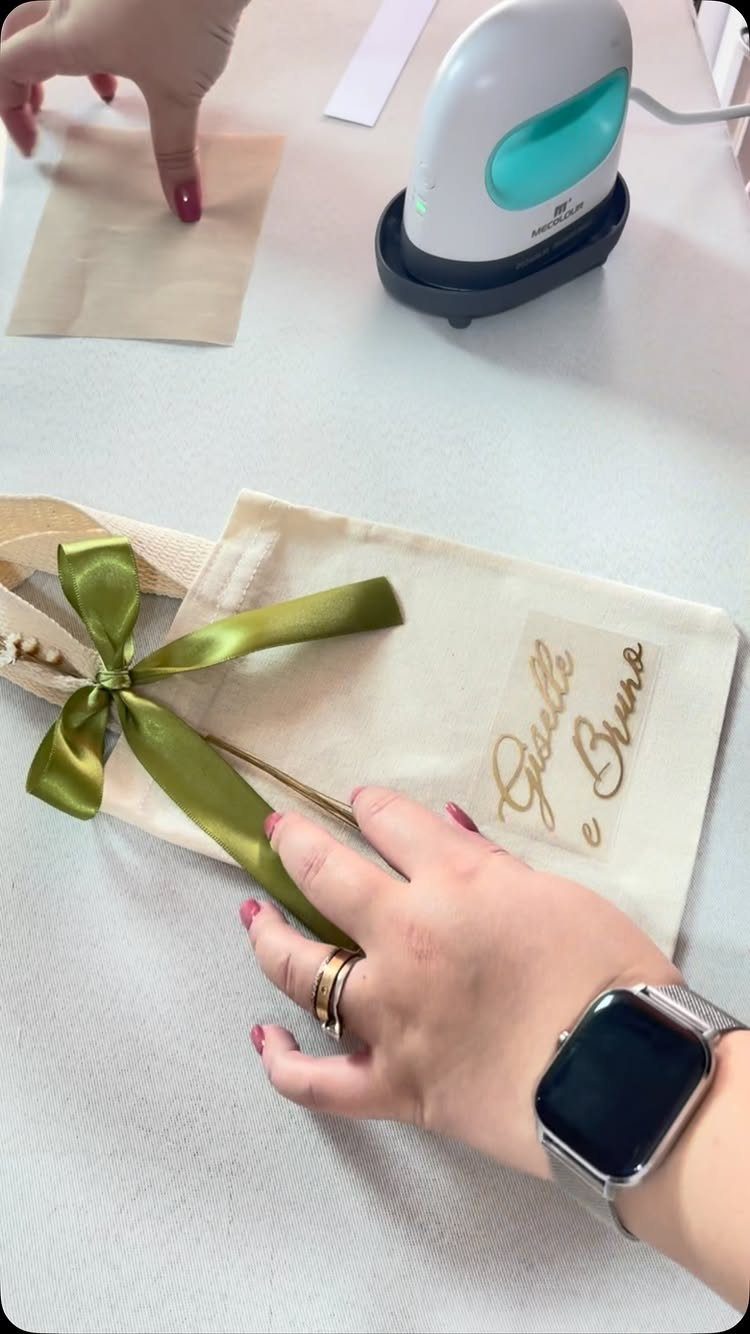 Small cream canvas tote bag with gold lettering and a green satin bow.