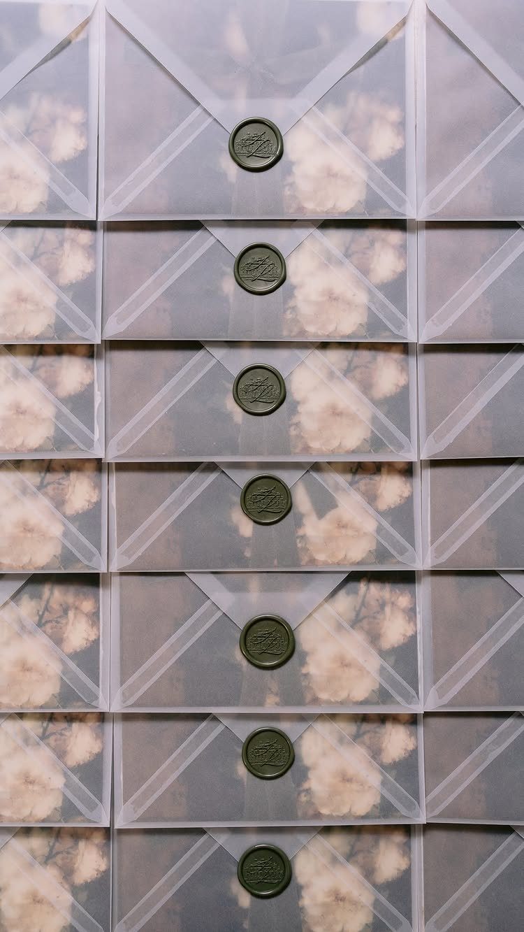 Translucent vellum envelopes with dark green wax seals and floral inserts inside.