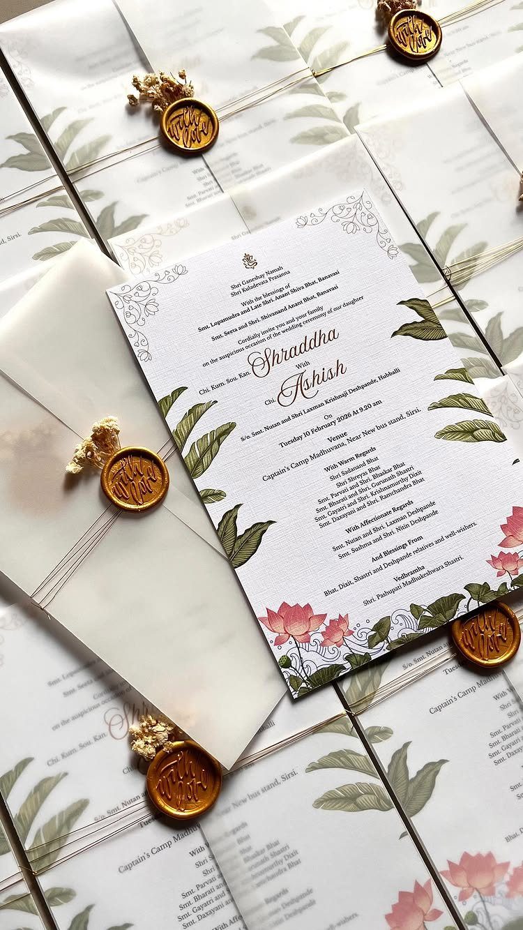 Wedding invitations with floral designs, vellum wraps, gold ribbons, and gold wax seals.