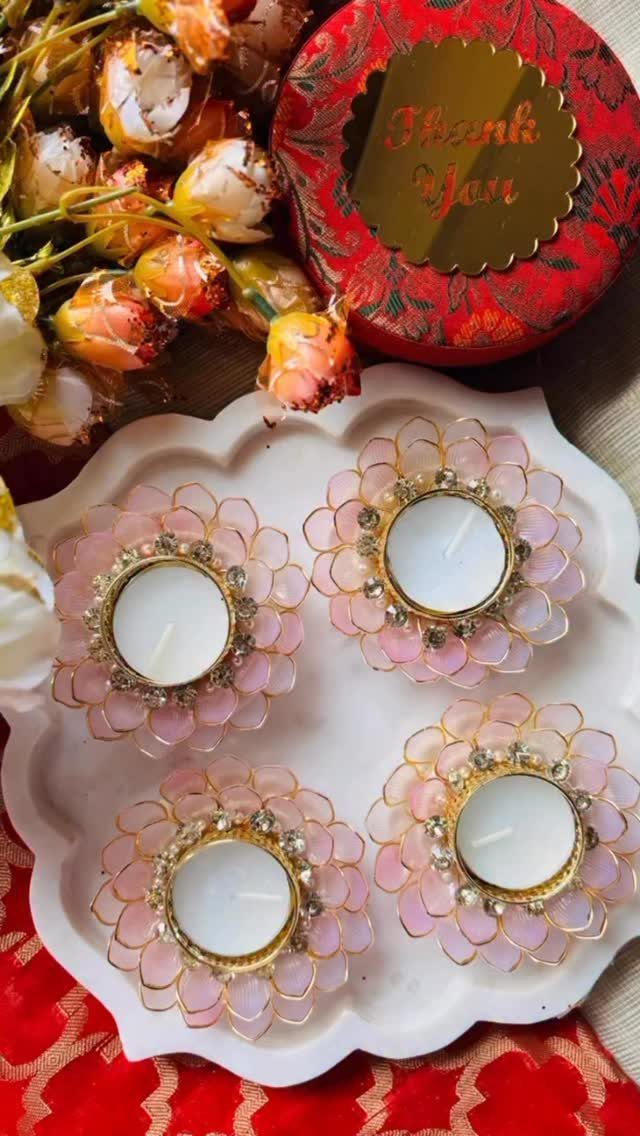 Four pink floral tea light candle holders on a white scalloped decorative tray.