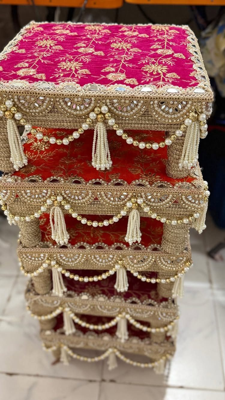 Decorative velvet gift trays with gold embroidery, pearls, and beaded tassels stacked vertically.