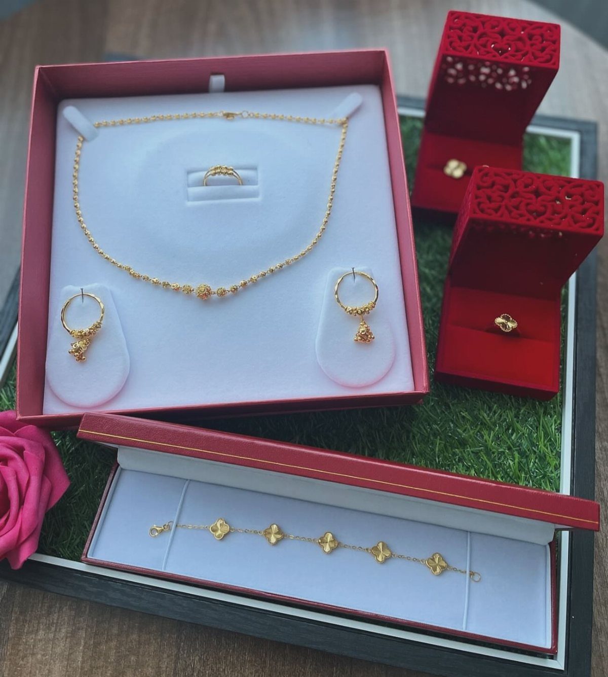 Gold jewelry set with necklace, earrings, and bracelet in red gift boxes.