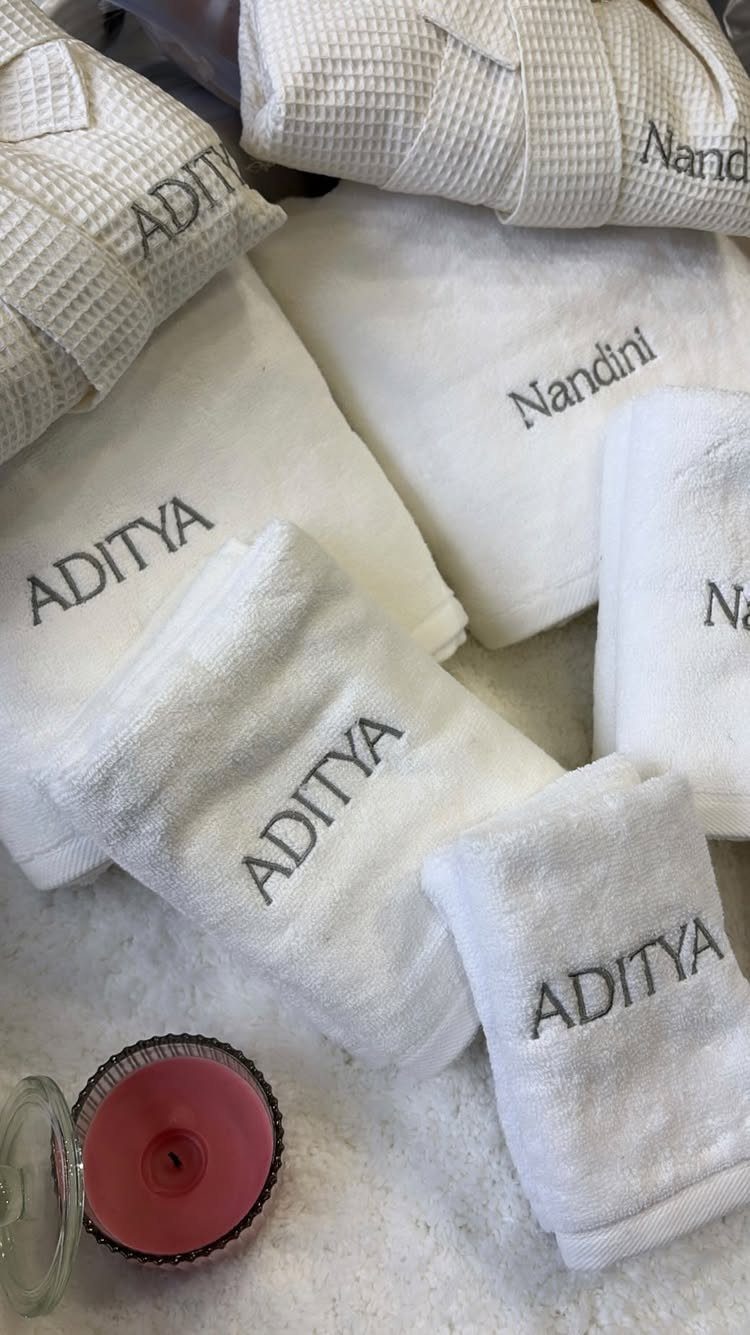 White embroidered towels and robes with a red candle for a spa set.