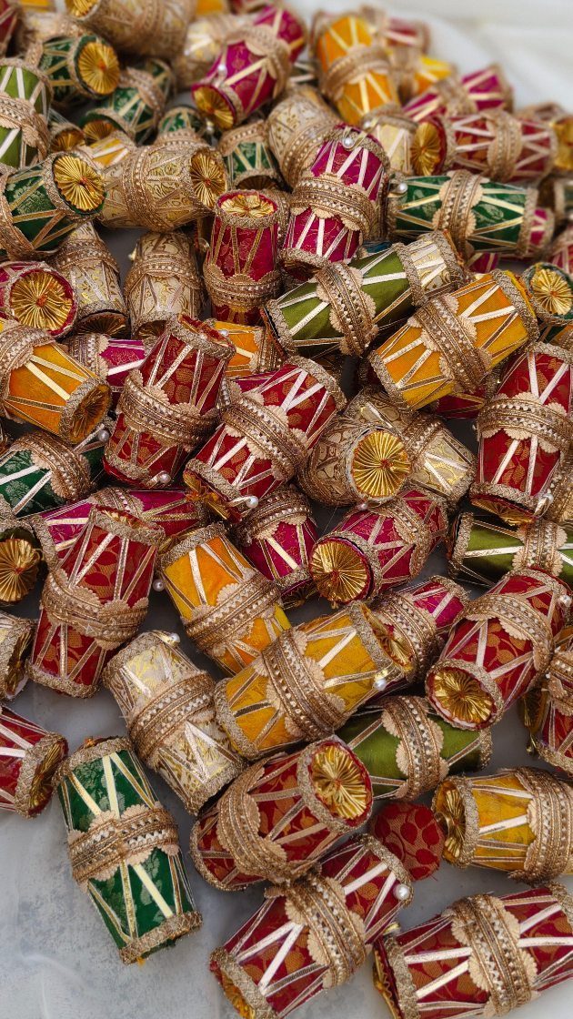 Small colorful decorative fabric drums with gold sequins piled on white background