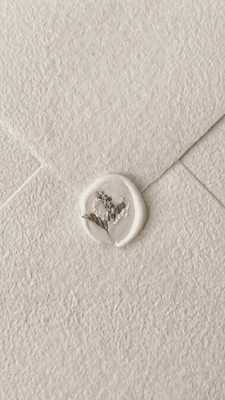 Textured off-white envelope sealed with a white wax seal and dried botanical sprig.