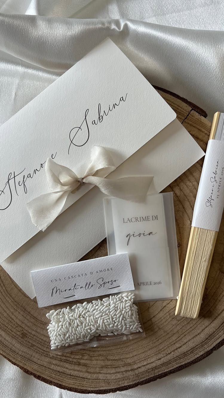White wedding invitation cards with calligraphy tied with a ribbon on wood.