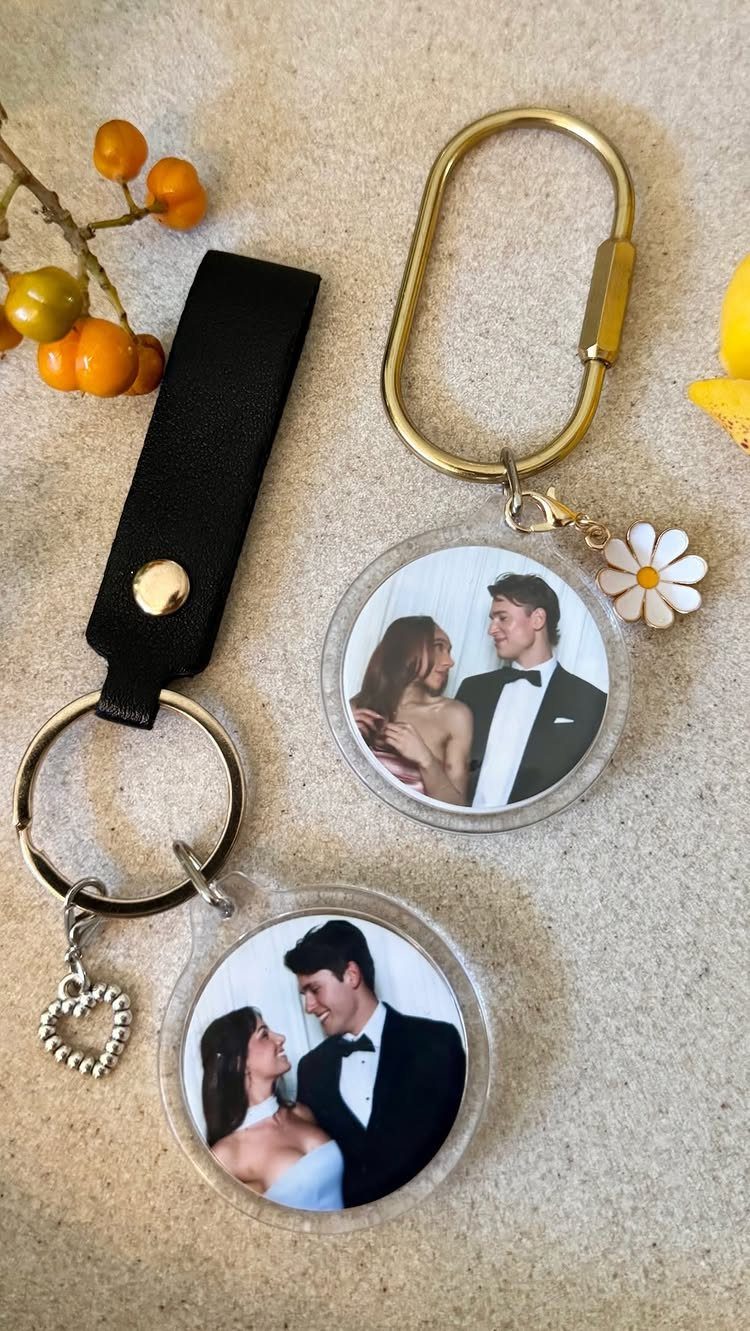 Two circular acrylic keychains with wedding photos of a couple on a textured background.
