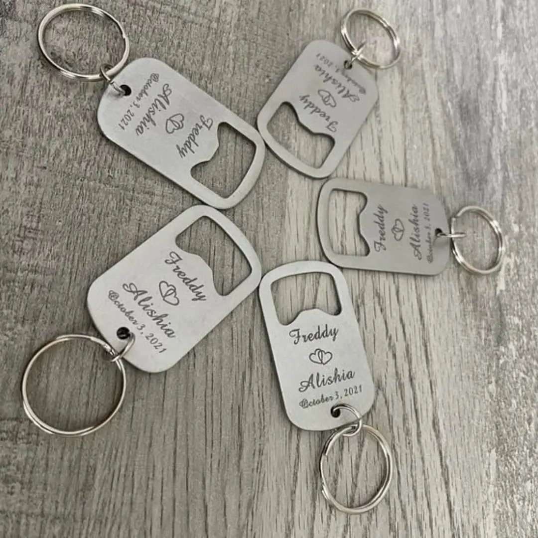 Silver metal bottle opener keychains engraved with names and a wedding date.