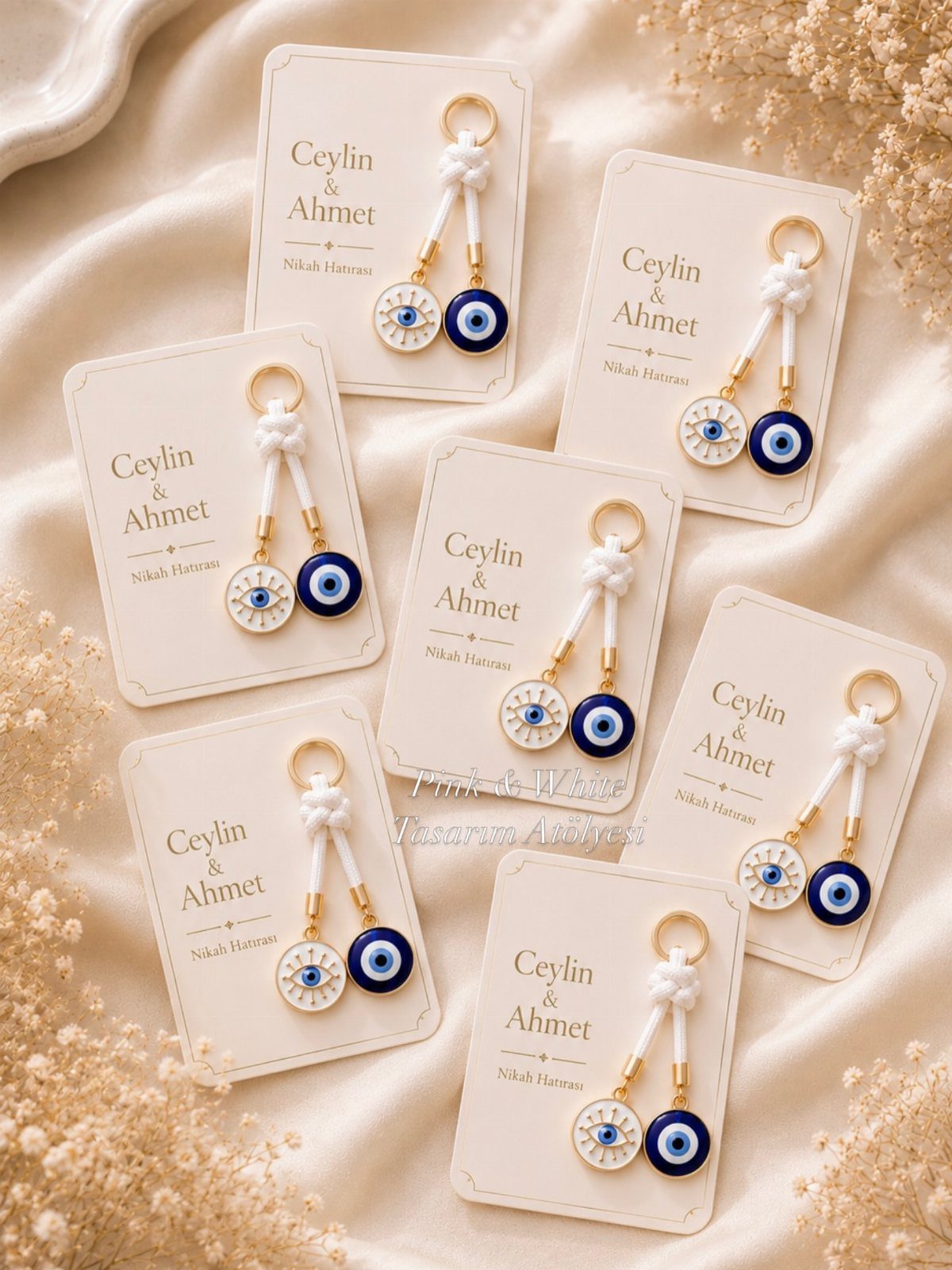 Evil eye bead keychains on personalized white cards resting on cream fabric.