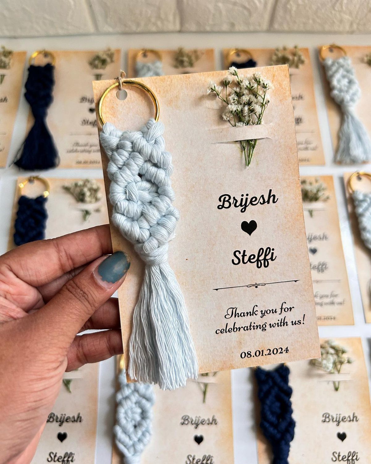 Light blue macrame keychain with tassel on a personalized wedding favor card.