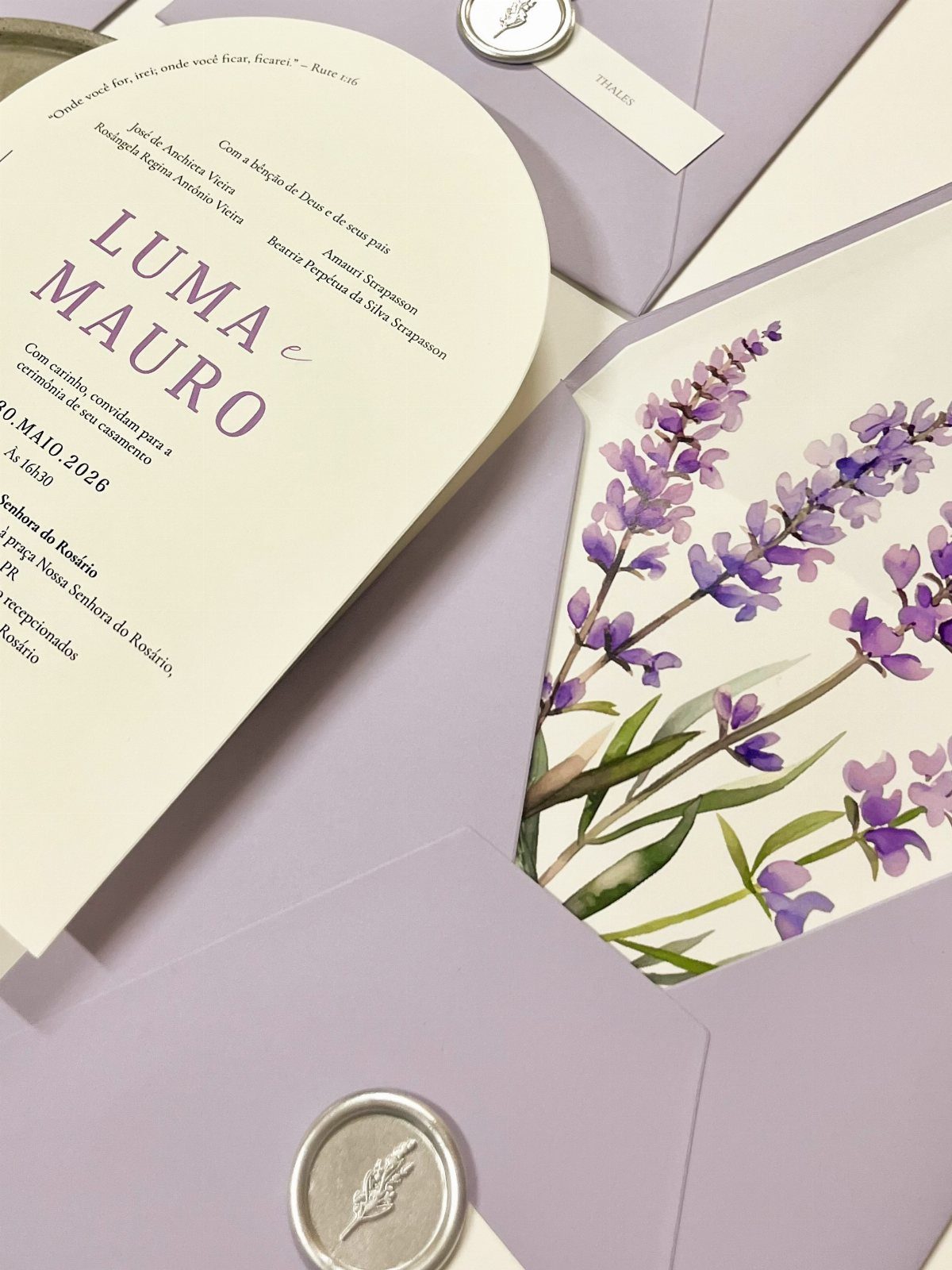 Wedding invitation set with watercolor lavender illustrations and light purple envelopes with wax seals.