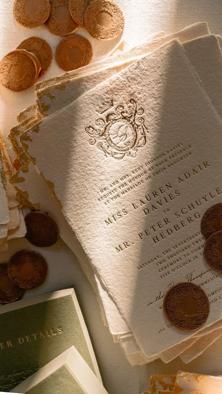 Textured white letterpress wedding invitations with gold wax seals and debossed typography.
