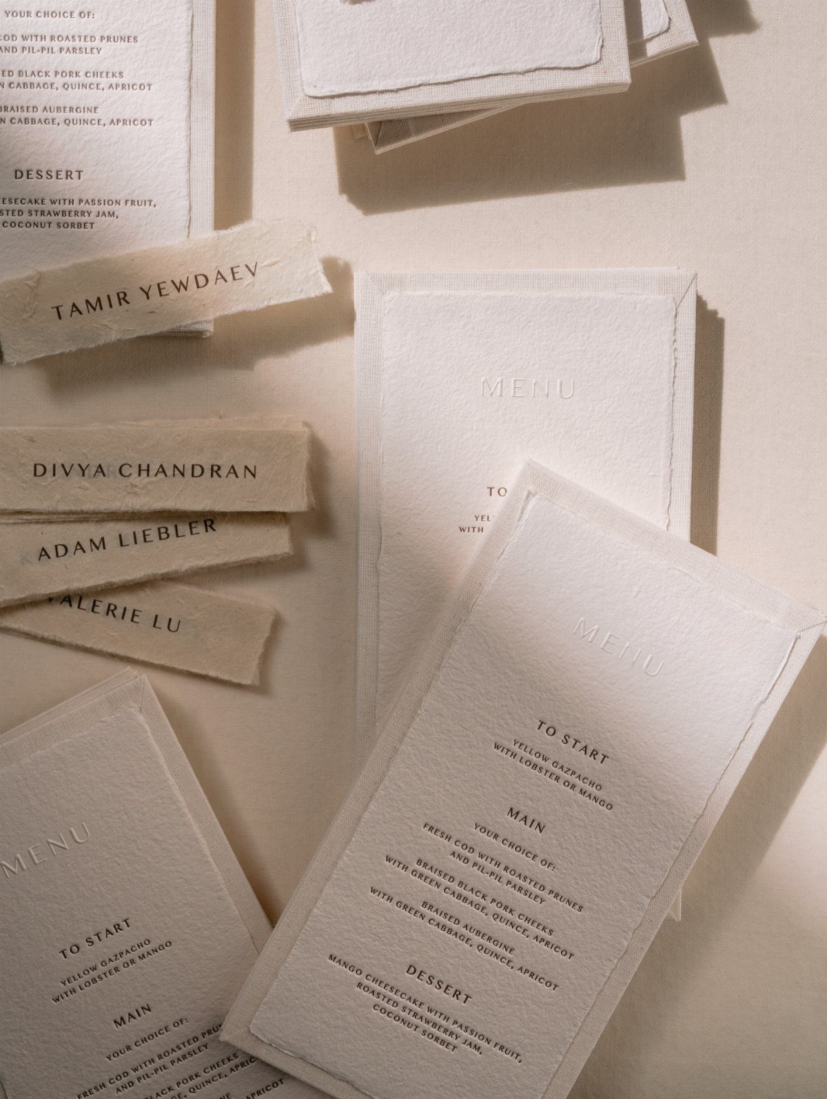 White debossed wedding menus and name cards with deckled edges on beige background