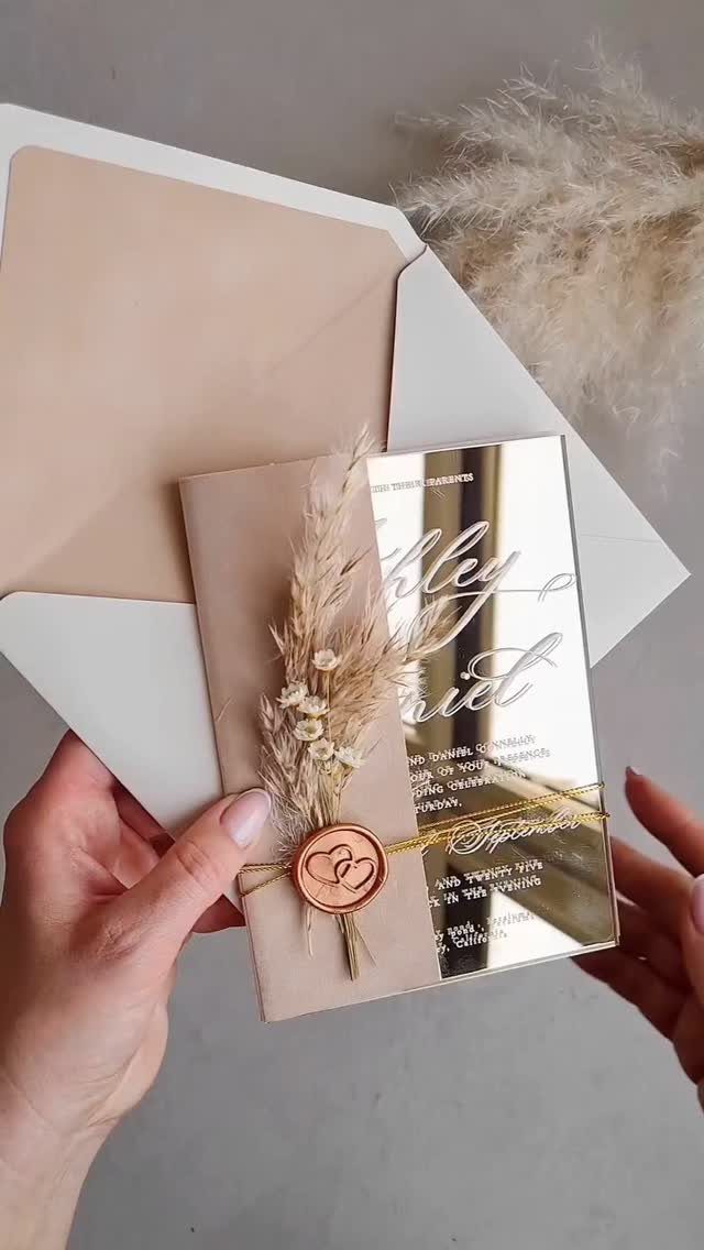 Wedding invitation with mirrored acrylic card, dried grass, and a copper wax seal.