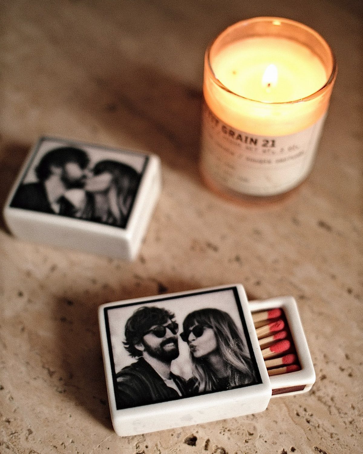 Two white matchboxes featuring black and white photos of a couple beside a candle.