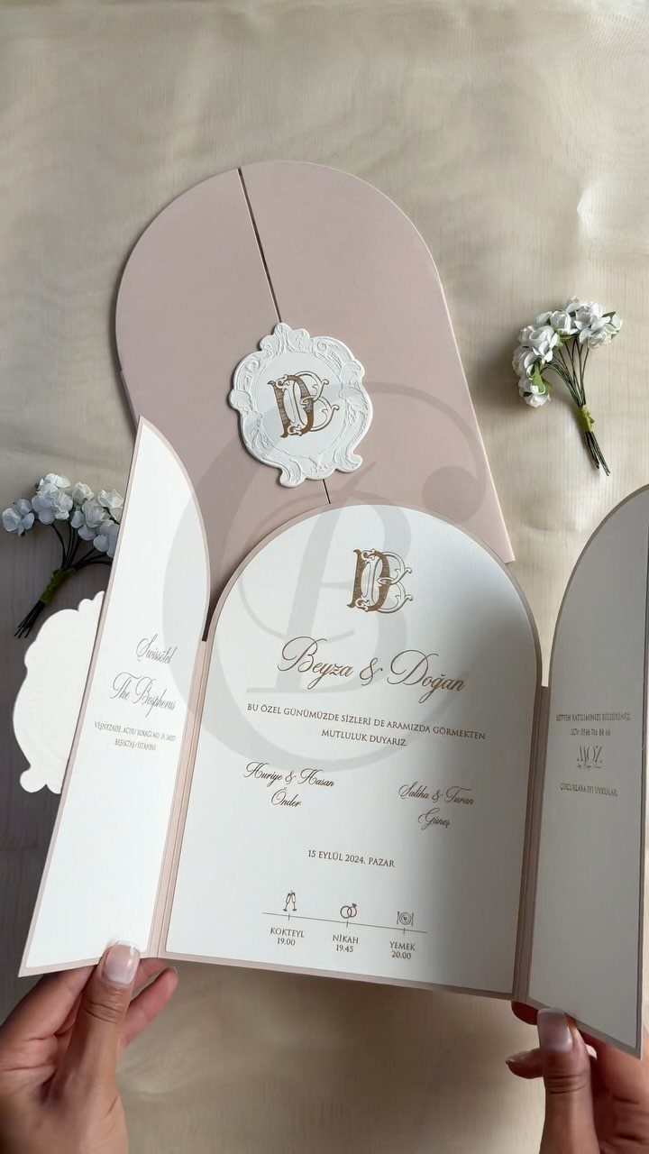 Arch-shaped wedding invitation suite in pale pink and white with gold calligraphy.