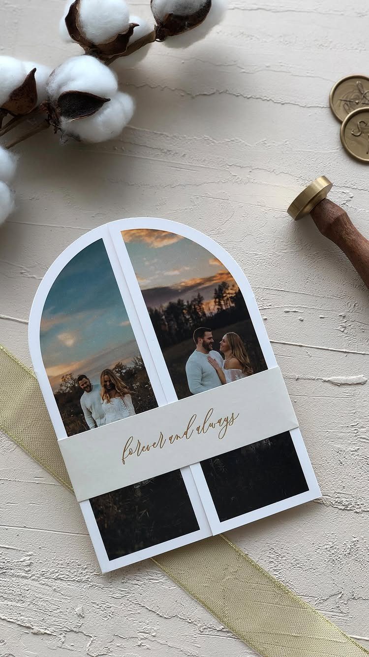 Arched wedding invitation with mountain landscape photos and gold cursive text on a band.