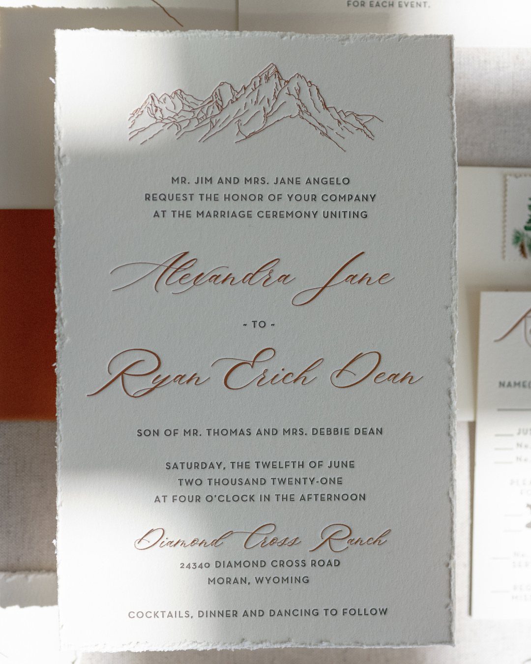 Wedding invitation with copper mountain illustration and elegant calligraphy on white textured paper.