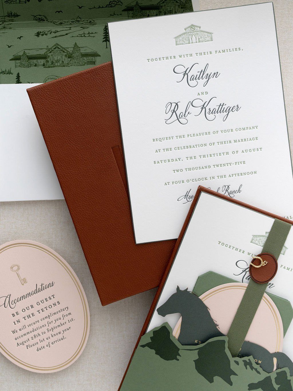 Wedding invitation suite with mountain illustrations, leather folder, and elegant script typography.