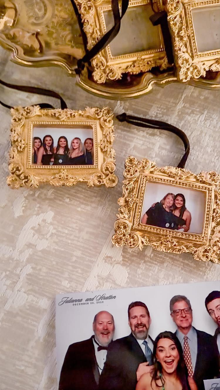 Small ornate gold frames with photos and black ribbons as wedding favor ornaments