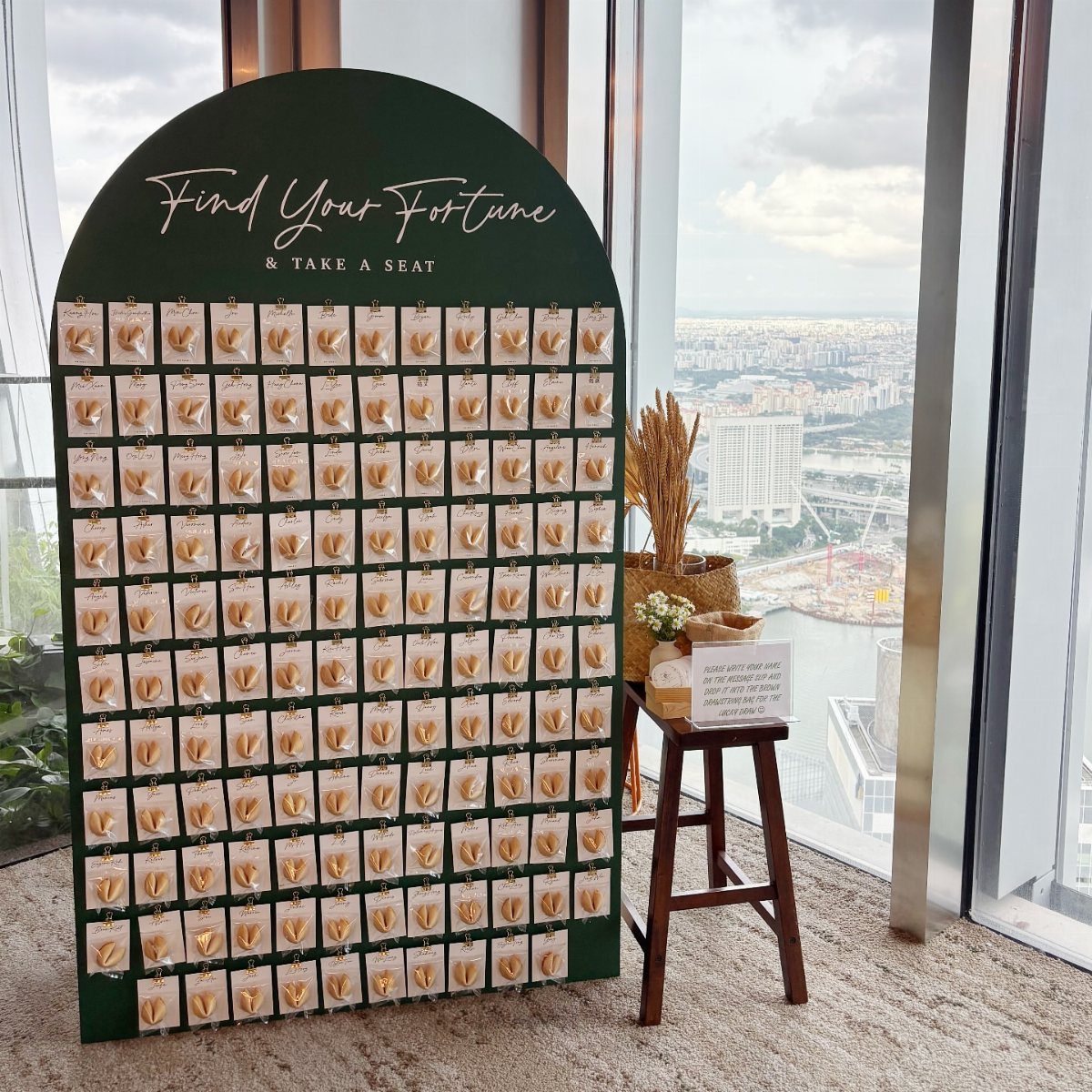 Green arched display board with gold text and pinned wedding favor cards.