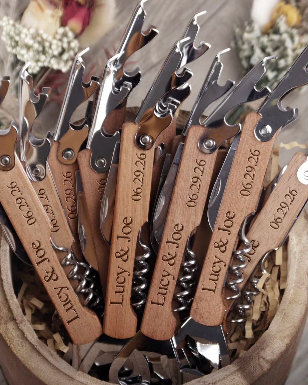 Engraved wooden and silver bottle openers gathered in a rustic wooden bowl.