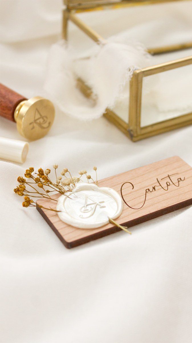 Wooden place card with engraved name, white wax seal, and dried yellow flowers.