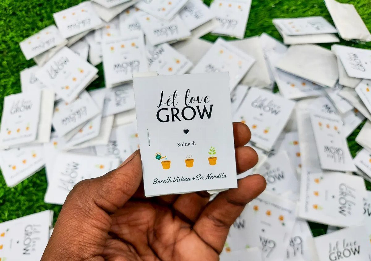 Seed packet with Let love GROW text held over scattered packets on grass